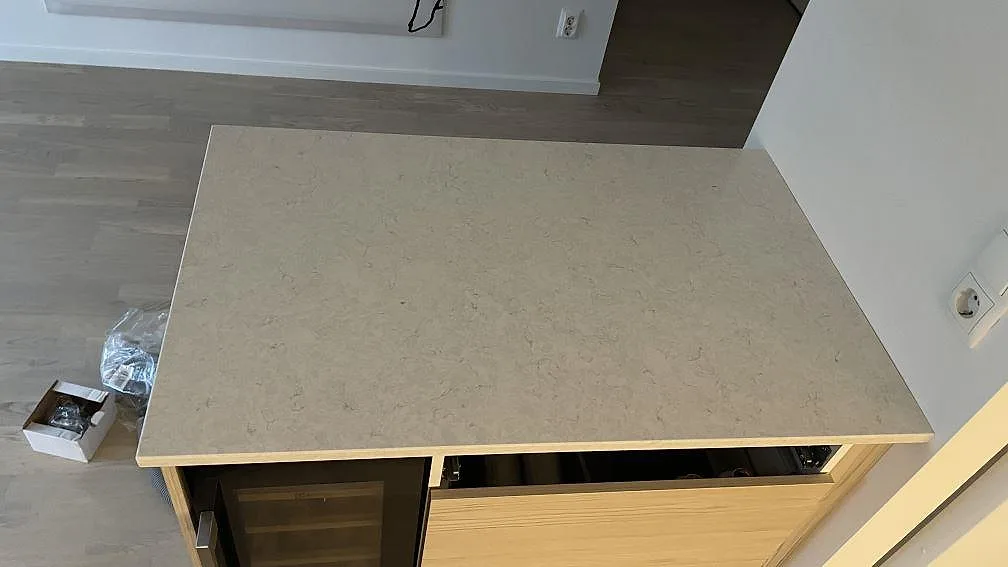 Köksö med bred arbetsyta i polerad Silestone Snowy Ibiza, ljus kvartskomposit med diskret ådring, fotograferad under montering i Malmö.