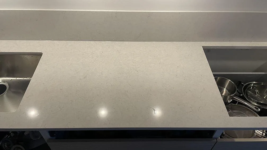Arbetsyta i polerad Silestone Snowy Ibiza mellan rostfri diskho och hällöppning, med ljus kvartskomposit och stänkskydd i Malmö.