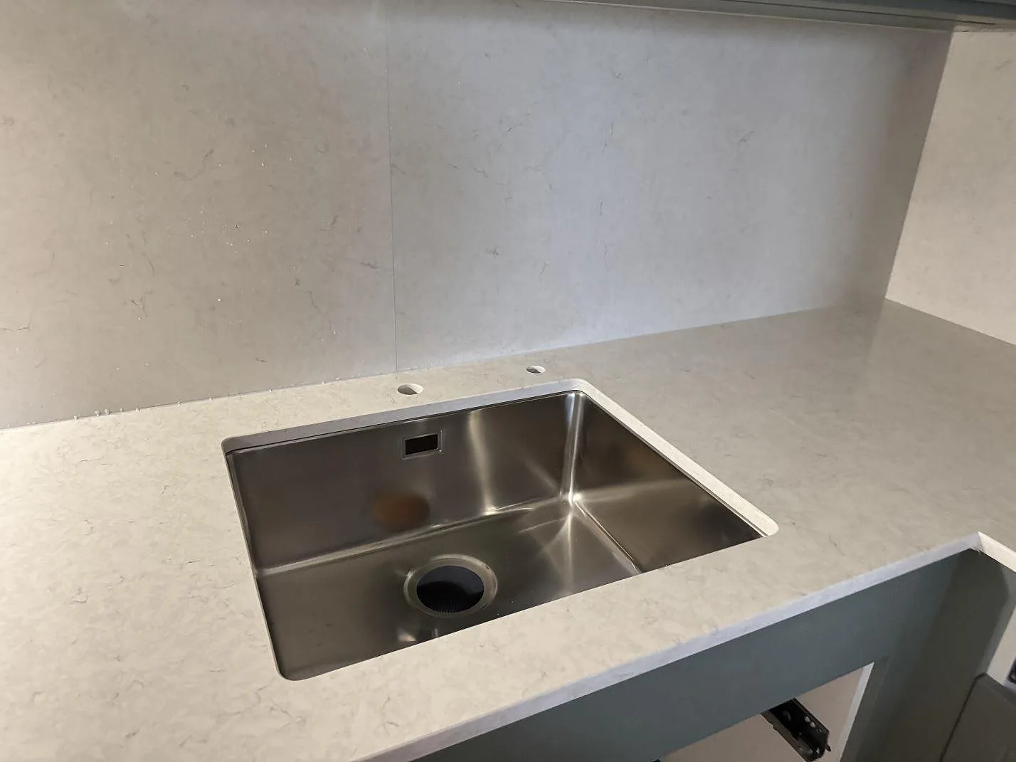 Diskhoområde i polerad Silestone Snowy Ibiza, ljus kompositbänkskiva med kranhål och stänkskydd i ett kök i Malmö.