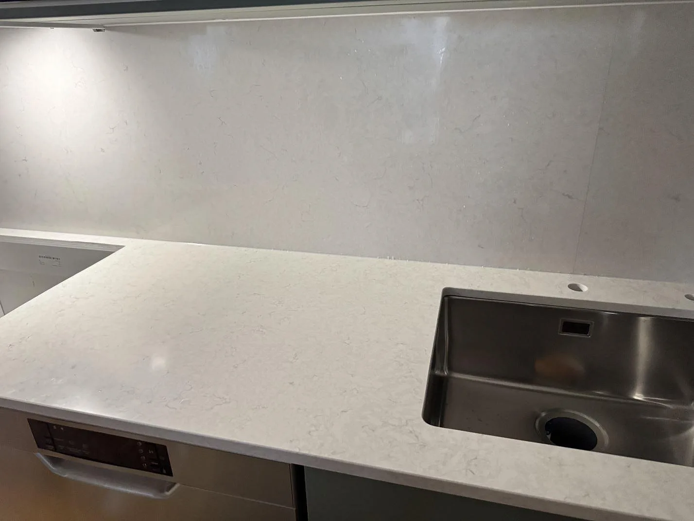 Lång köksbänk i polerad Silestone Snowy Ibiza med diskho, stänkskydd och integrerad vitvara under stenen i Malmö.