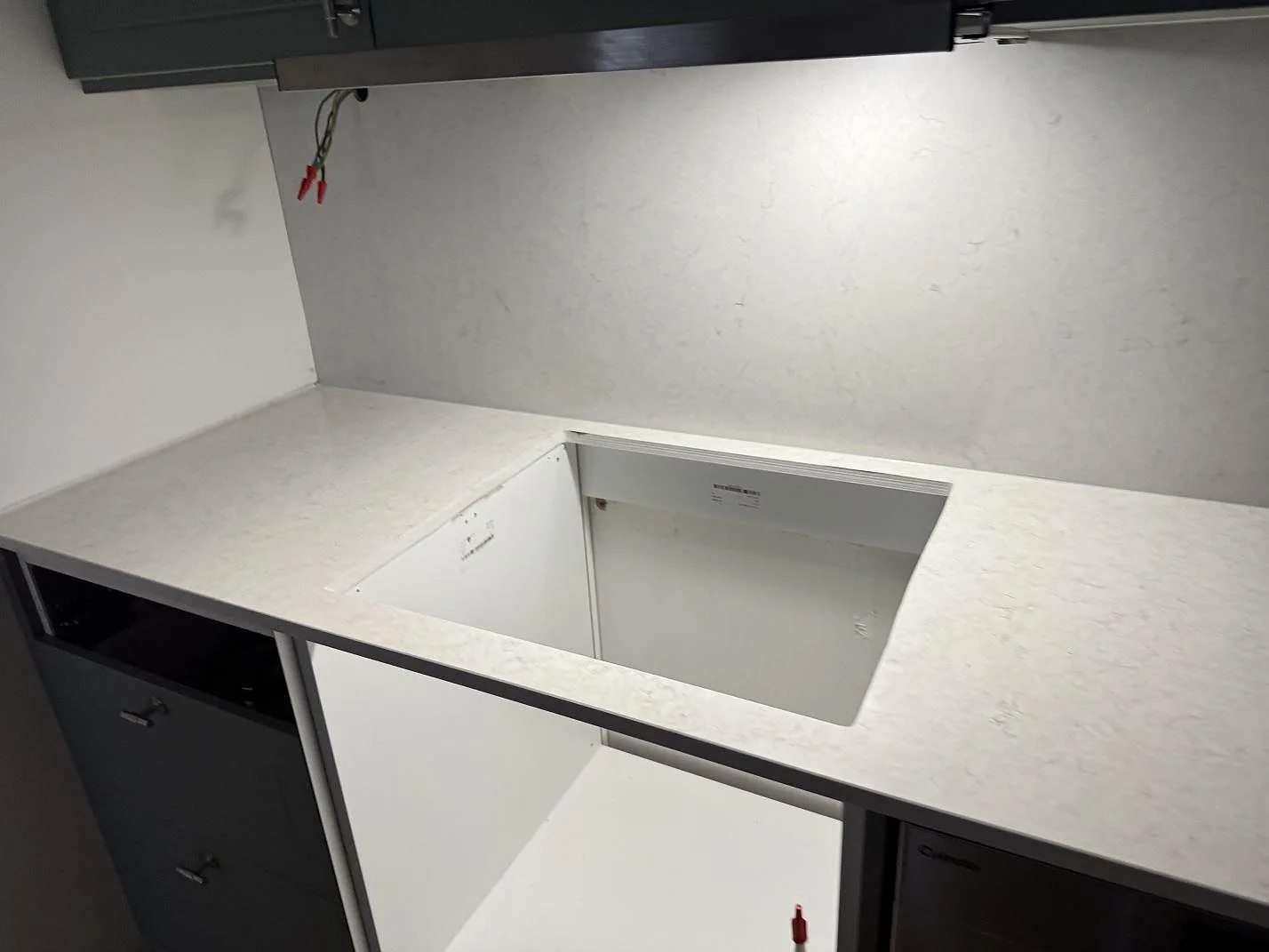 Närmare vy av polerad Silestone Snowy Ibiza runt en större öppning i köksbänken, med ljus komposityta och väggskiva i Malmö.