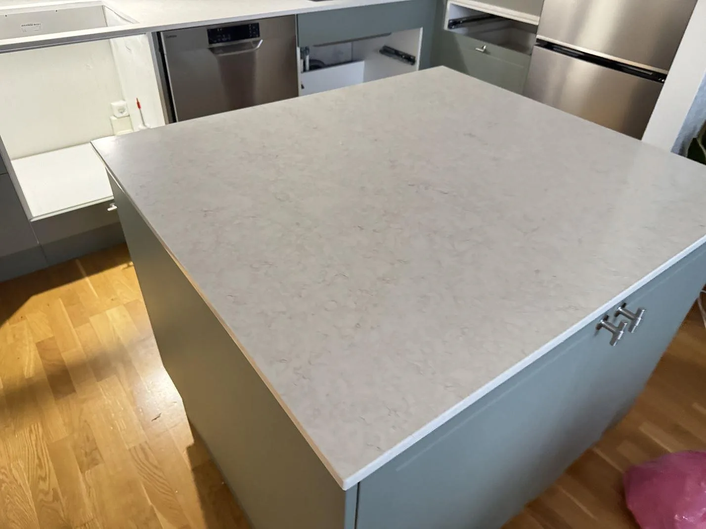 Köksö med bänkskiva i polerad Silestone Snowy Ibiza, ljus komposit med mjuk ådring, i ett kök under montering i Malmö.
