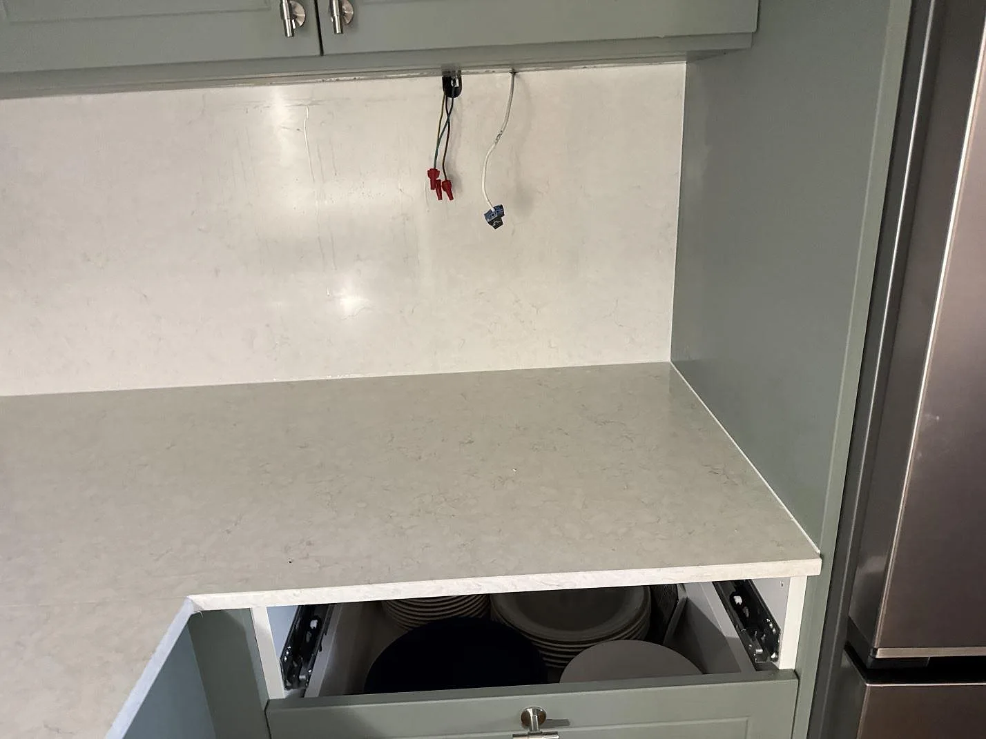 Höger bänksträcka i polerad Silestone Snowy Ibiza med ljus väggbeklädnad och öppna stommar under montering i Malmö.