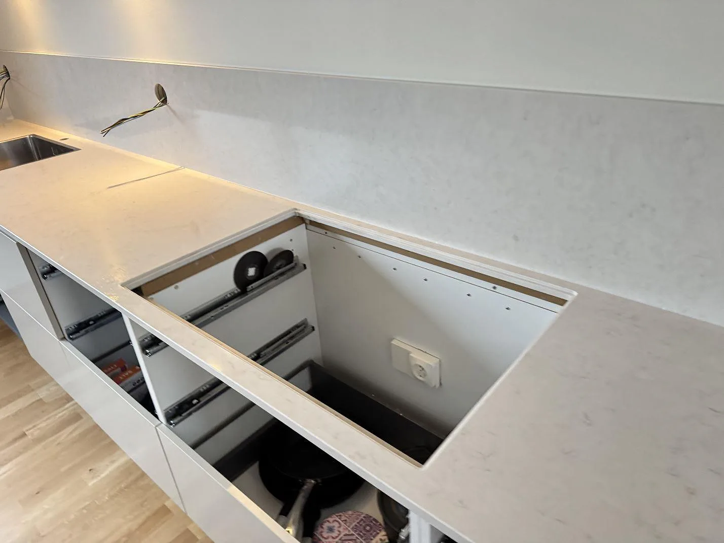 Vit polerad Silestone Snowy Ibiza köksbänk med öppen hålurtagning för häll över lådstommarna under pågående montering i ett kök i Malmö.