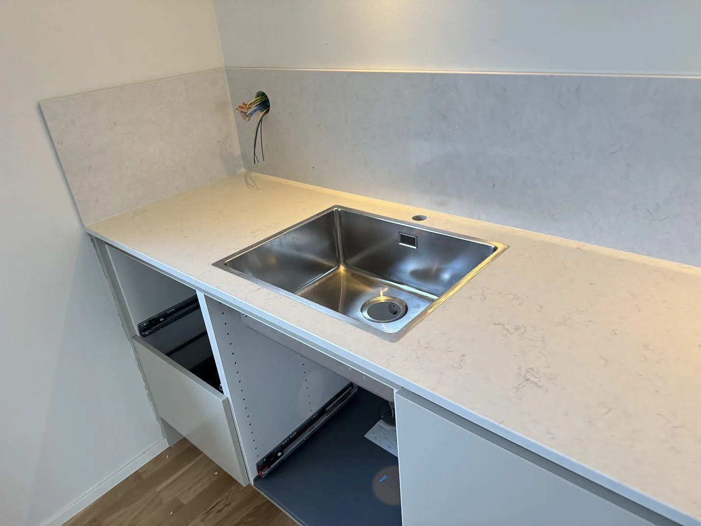 Underlimmad rostfri diskho infälld i vit polerad Silestone Snowy Ibiza med uppvikt stänkskydd i samma sten i ett kök i Malmö.