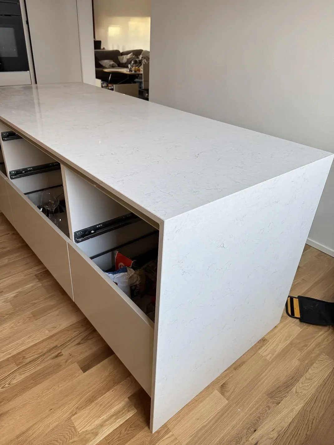 Halvö med köksbänk i vit Silestone Snowy Ibiza där stenen viks ner i en gavel längs sidan, fotograferad under montering i ett kök i Malmö.