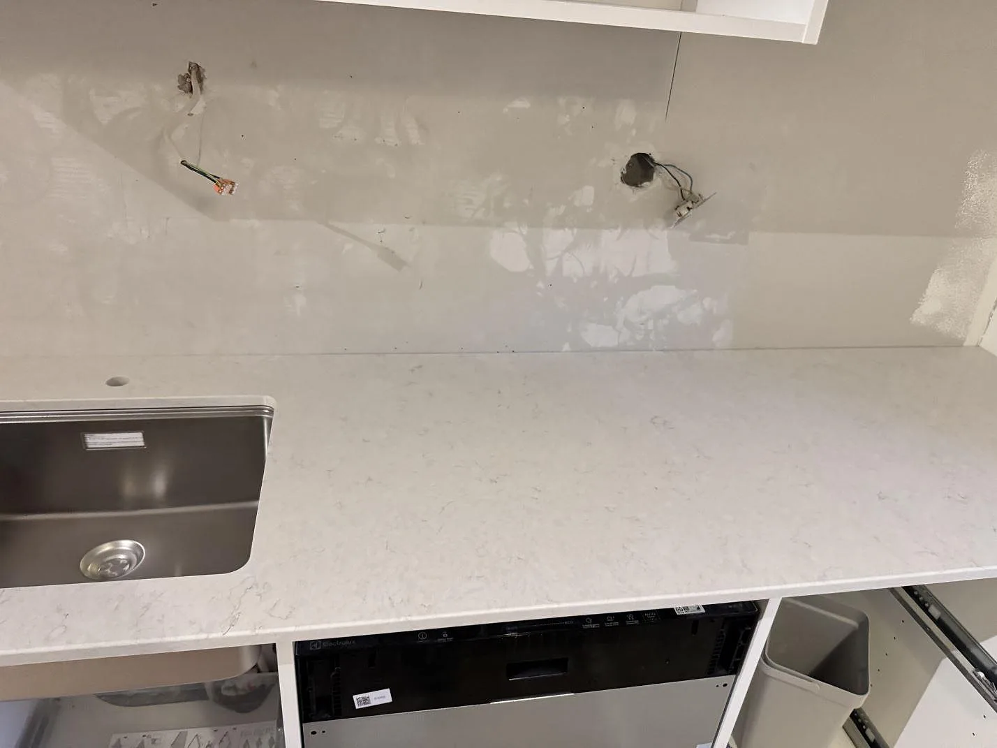 Underlimmad rostfri diskho i en vit Silestone Snowy Ibiza-bänkskiva med integrerad diskmaskin under, i ett kök under montering i Malmö.