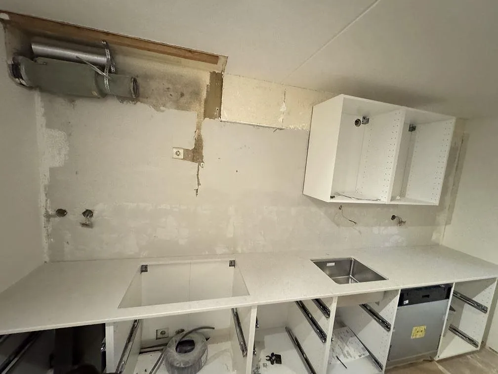 Köksbänkskiva i vit Silestone Snowy Ibiza, polerad, med underlimmad rostfri diskho och förberett hällurtag i en L-formad bänk i ett kök under montering i Malmö.