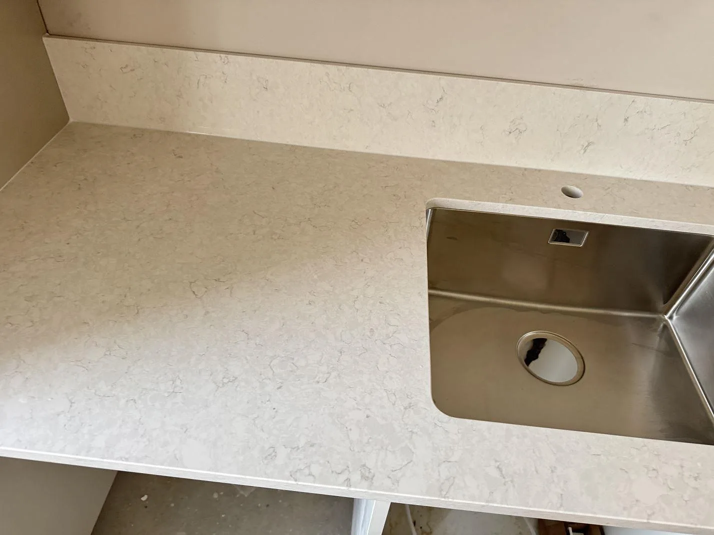Närbild på köksbänkskiva i polerad Silestone Snowy Ibiza med rostfri diskho och stänkskydd i Mamö.