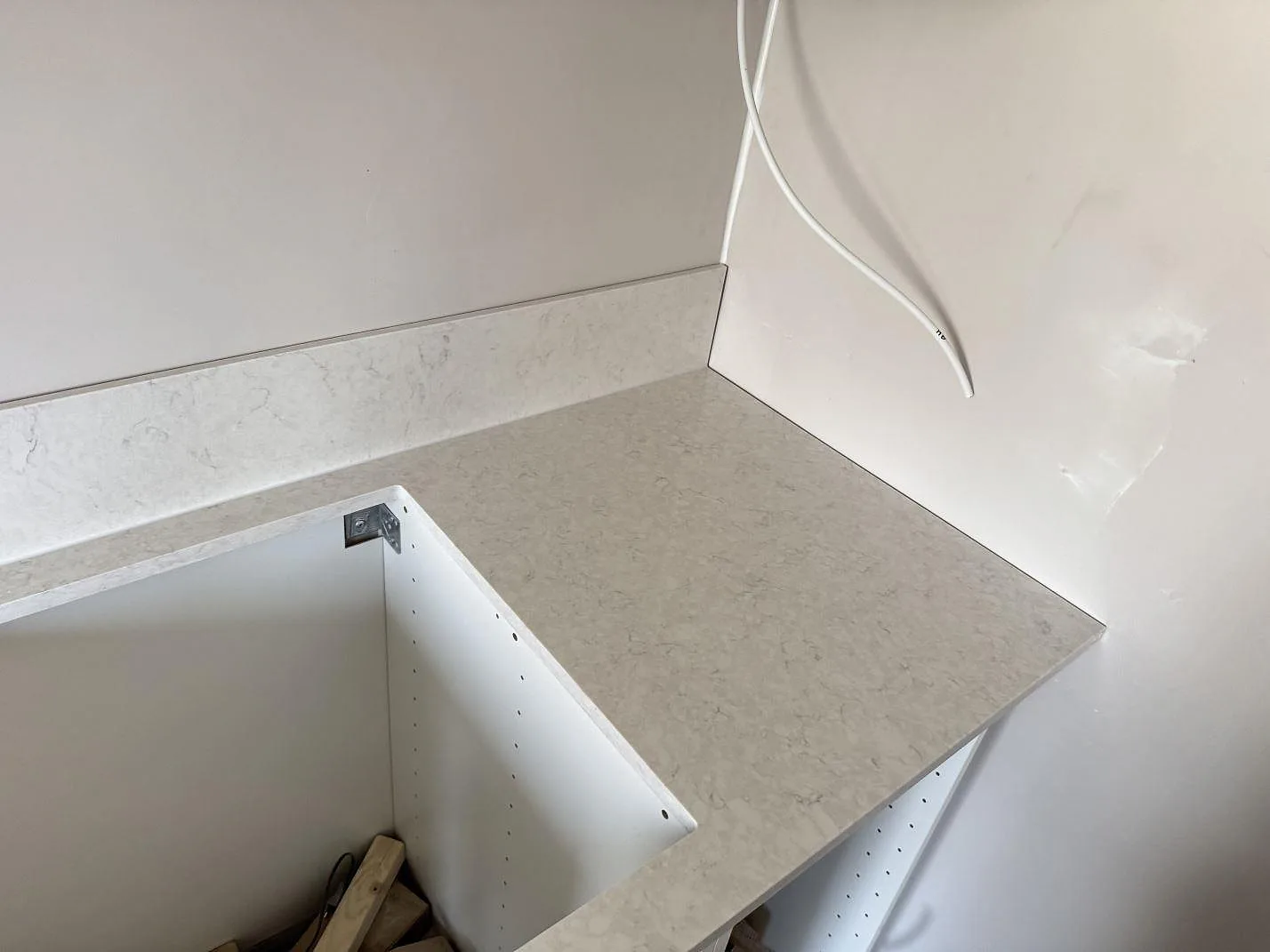 Höger del av köksbänkskiva i polerad Silestone Snowy Ibiza med 12 mm stänkskydd under montering i Mamö.