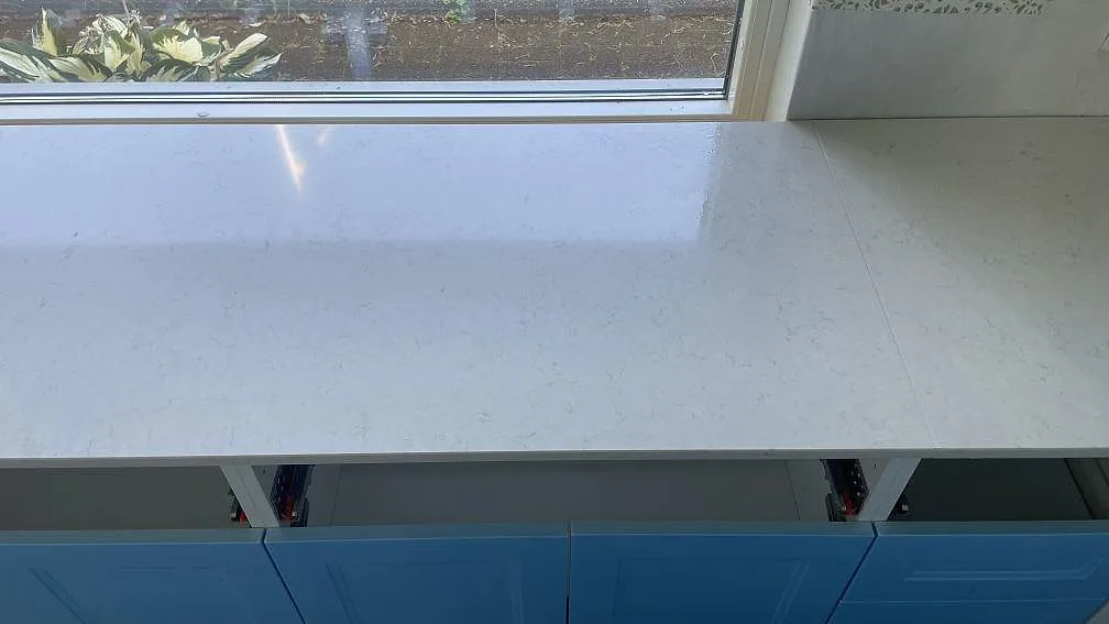 Närbild på lång vit Silestone Snowy Ibiza bänkrad, polerad, framför fönster i ett kök i Mellbystrand.
