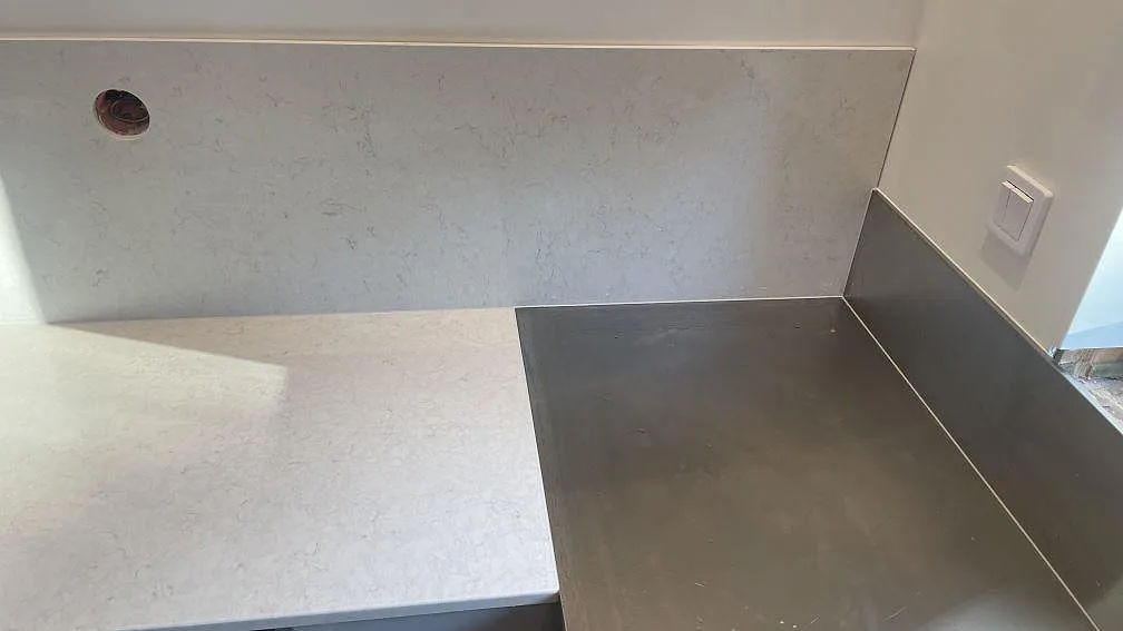 Polerad Silestone Snowy Ibiza kvartskomposit vid övergången mellan bänkskiva, stänkskydd och separat rostfri diskzon i Mölndal.