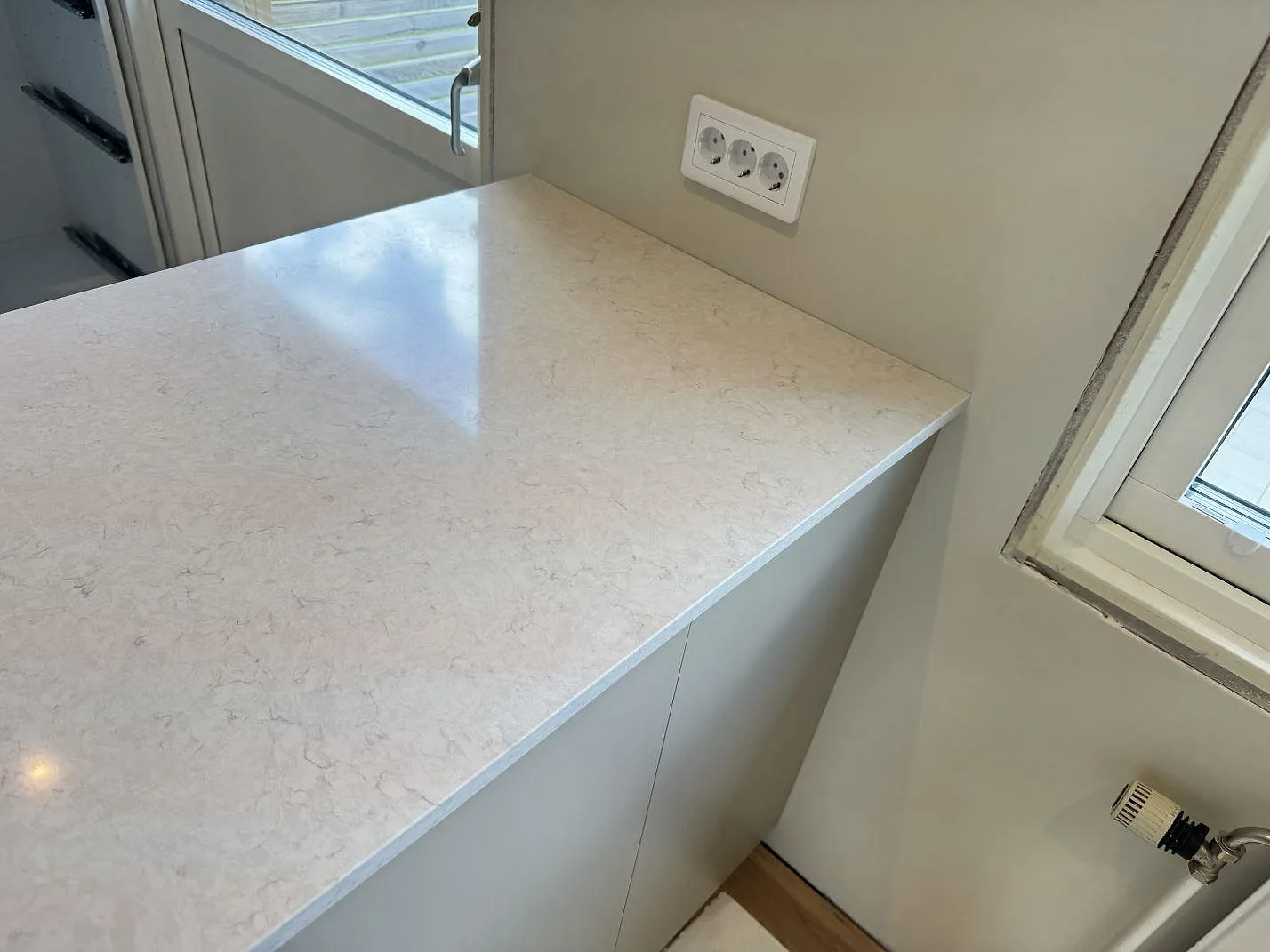 Närbild på polerad Silestone Snowy Ibiza som köksbänkskiva intill vägguttag och fönster i Mörrum.