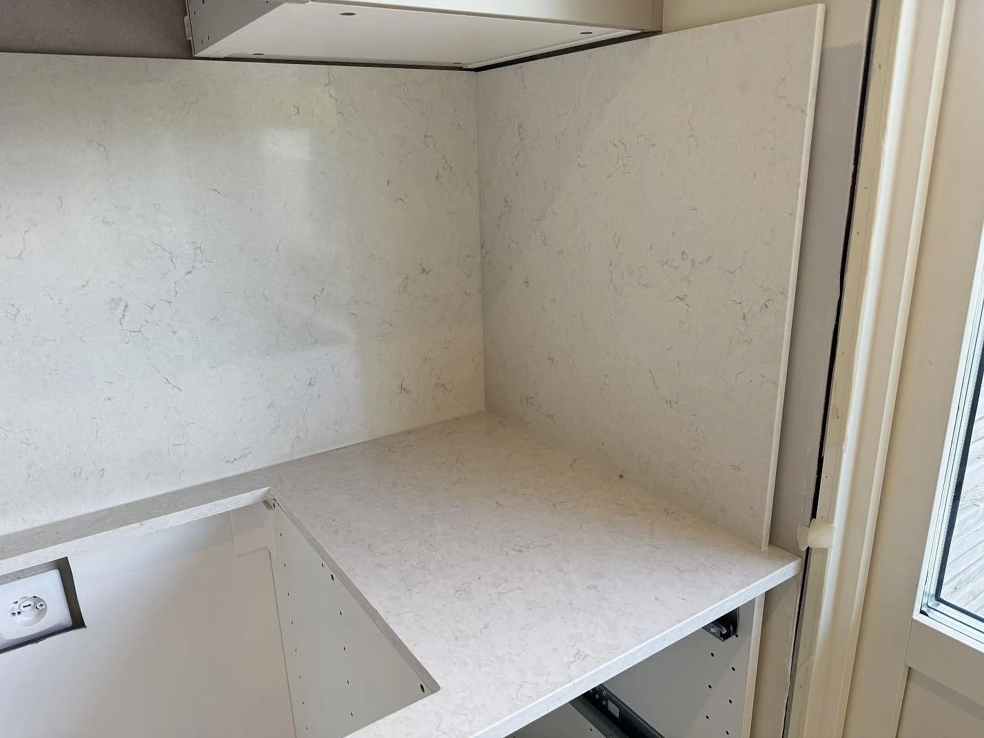 Polerad Silestone Snowy Ibiza som bänkskiva och stänkskydd under köksfläkt i ett kök i Mörrum.