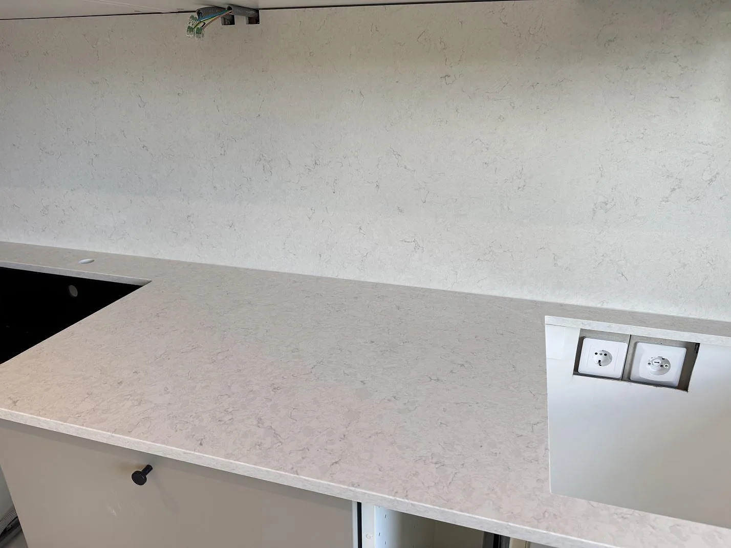 Bänkskiva och stänkskydd i polerad Silestone Snowy Ibiza med synlig svart diskho i kök i Mörrum.