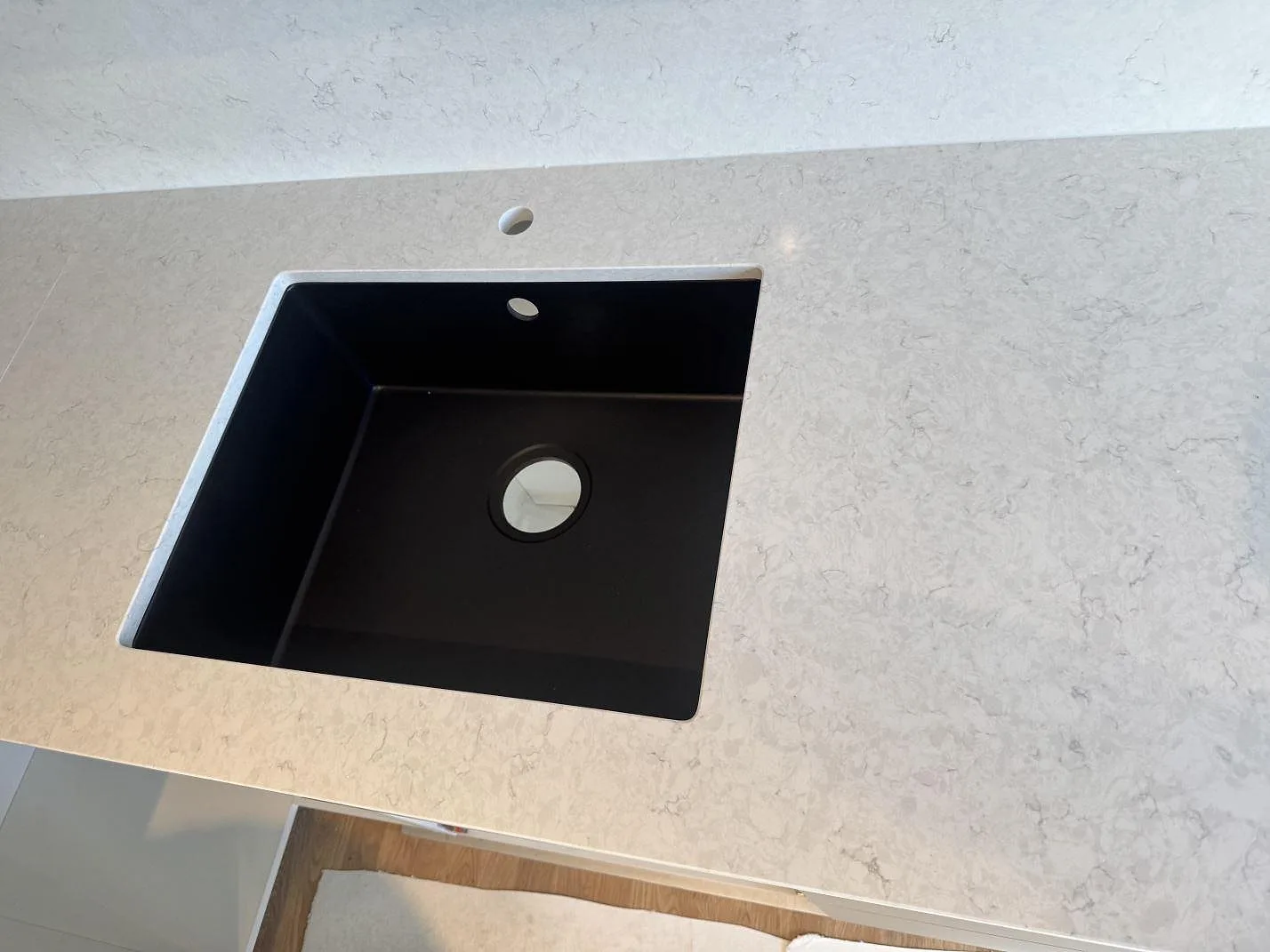 Närbild på svart diskho i polerad Silestone Snowy Ibiza med ljus kvartskomposit runt arbetsytan i Mörrum.
