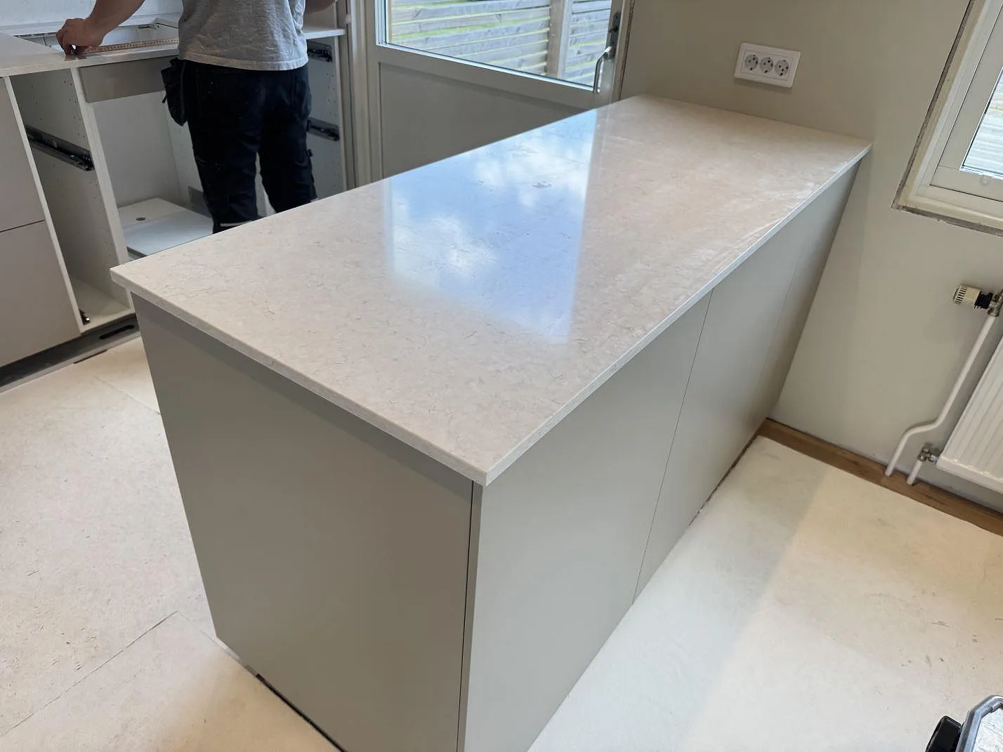 Polerad köksbänkskiva i Silestone Snowy Ibiza med ljus grå mönstring och pågående montering i Mörrum.