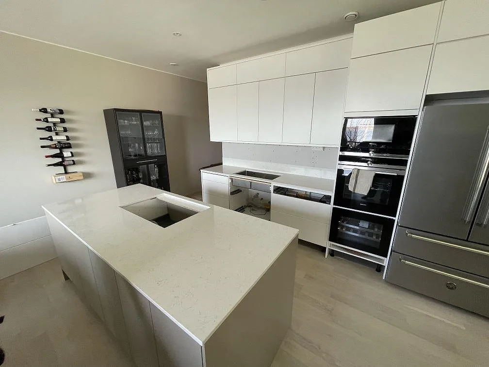 Vit köksbänkskiva i Silestone Snowy Ibiza, polerad, med köksö och väggbänk i Nacka strand.