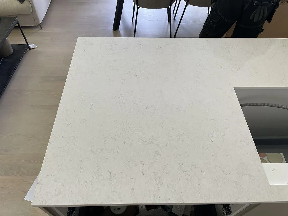 Topvy av vit Silestone Snowy Ibiza, polerad kvartskomposit, med hällöppning och grå ådring i Nacka strand.