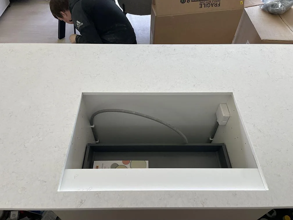 Detalj av hällöppning i polerad Silestone Snowy Ibiza på köksö under montering i Nacka strand.