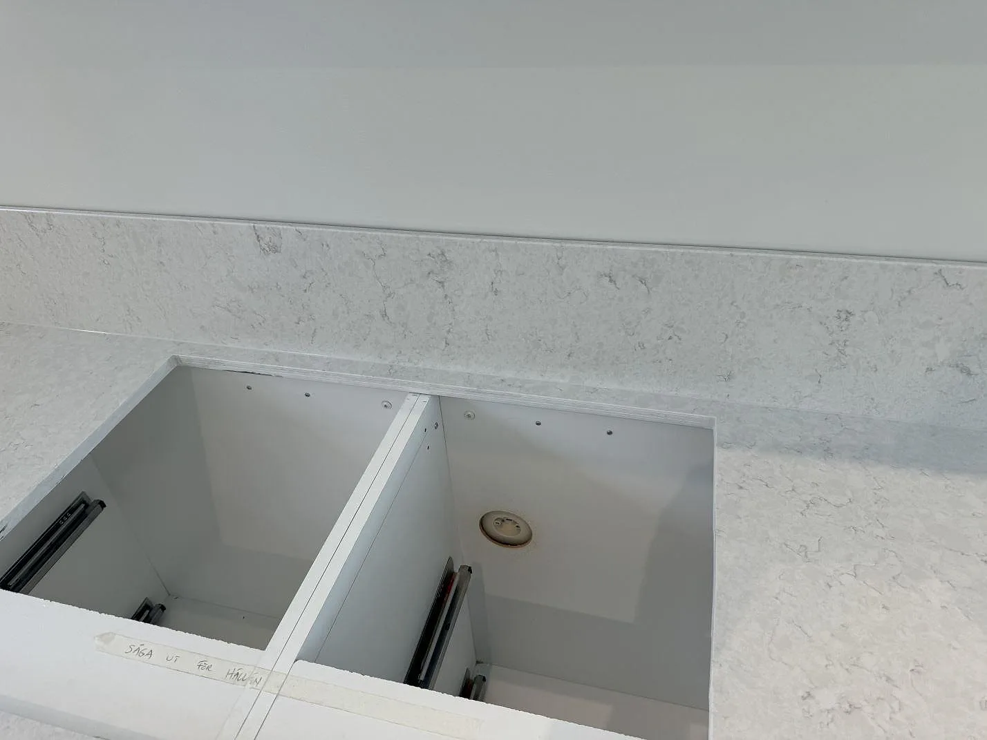 Närbild av öppning i polerad Silestone Snowy Ibiza bänkskiva, med låg stänkkant och monteringsmarkering i köket i Nättraby.