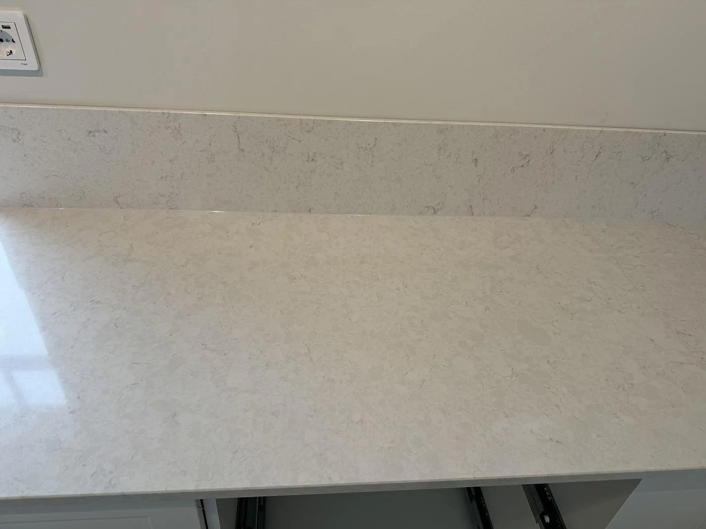 Rak detalj av polerad Silestone Snowy Ibiza bänkskiva med matchande stänkkant och synlig ljus ådring i Nättraby.