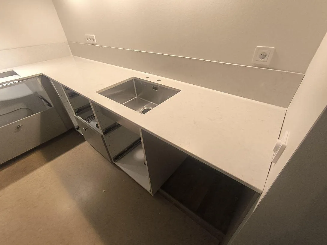 Diskhozon i polerad Silestone Snowy Ibiza, vit kompositbänkskiva med låg stänkkant i ett kök i Norrköping.