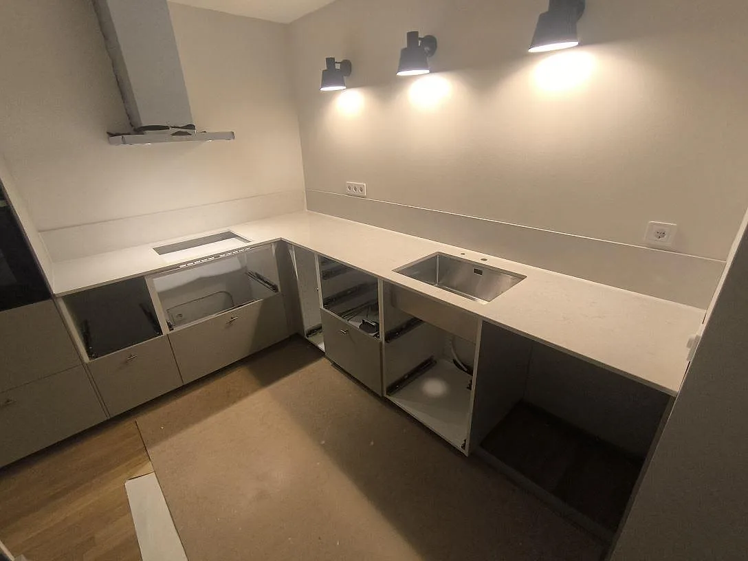 L-formad köksbänkskiva i polerad Silestone Snowy Ibiza med uppvikt stänkkant, hällöppning och diskho i Norrköping.
