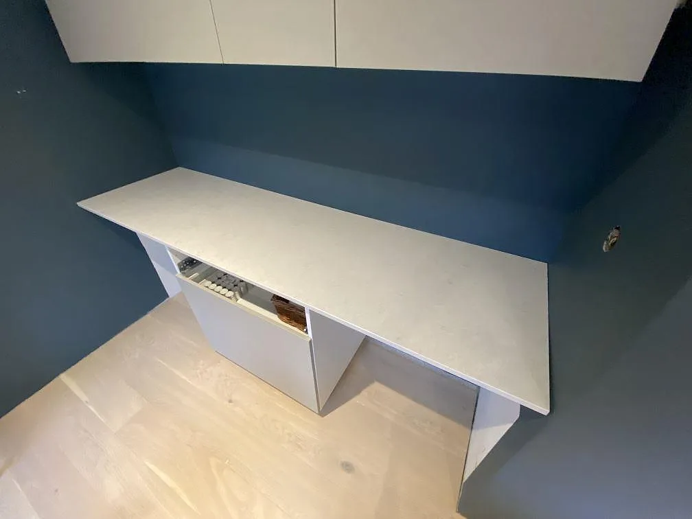 Avlastningsbänk i vit Silestone Snowy Ibiza på ett lågt skåp längs en djupblå vägg i ett kök i Österskär.