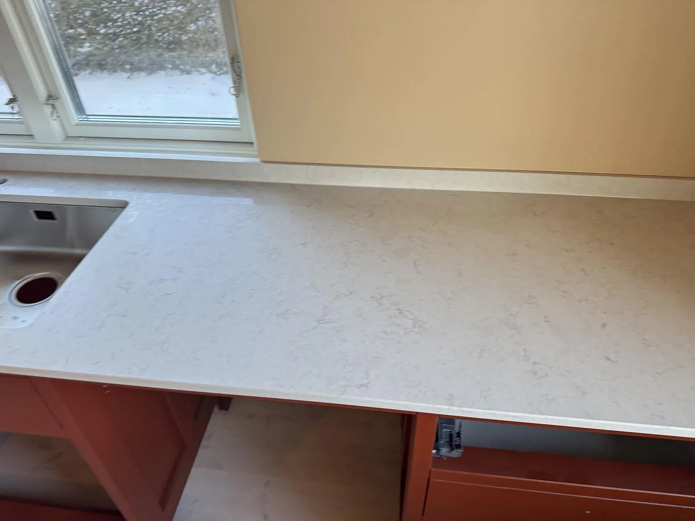 Matt vit Silestone Snowy Ibiza bänkskiva med underlimmad rostfri diskho i ett kök under montering i Östra Vemmerlöv.