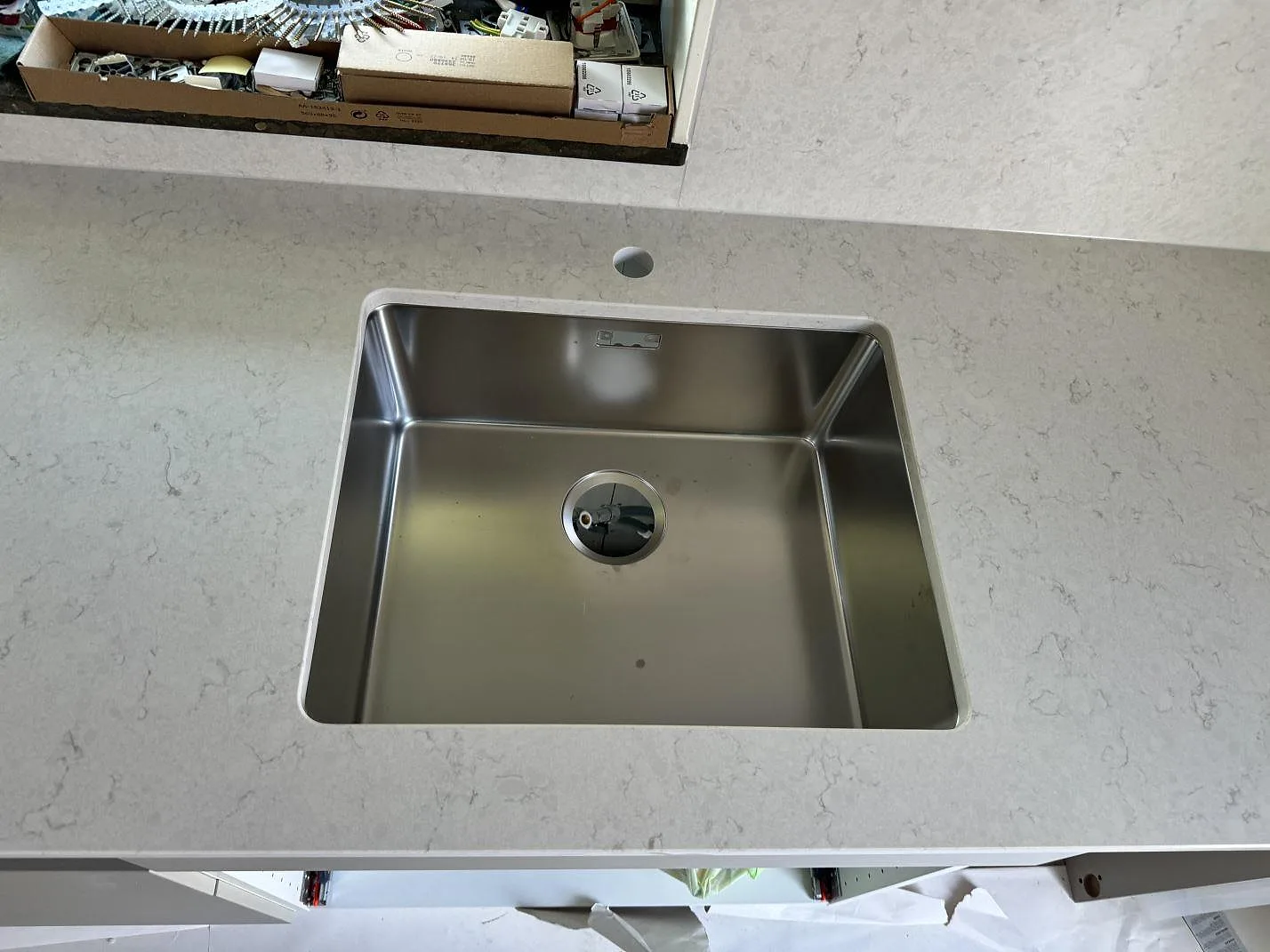 Närbild på underlimmad rostfri diskho i polerad Silestone Snowy Ibiza komposit i ett kök i Ojersjo.