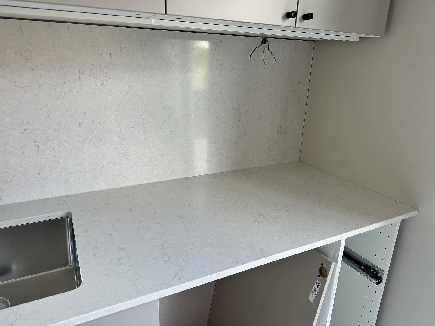 Rak köksbänk i polerad Silestone Snowy Ibiza med väggbeklädnad, överskåp och öppna vita stommar i Ojersjo.