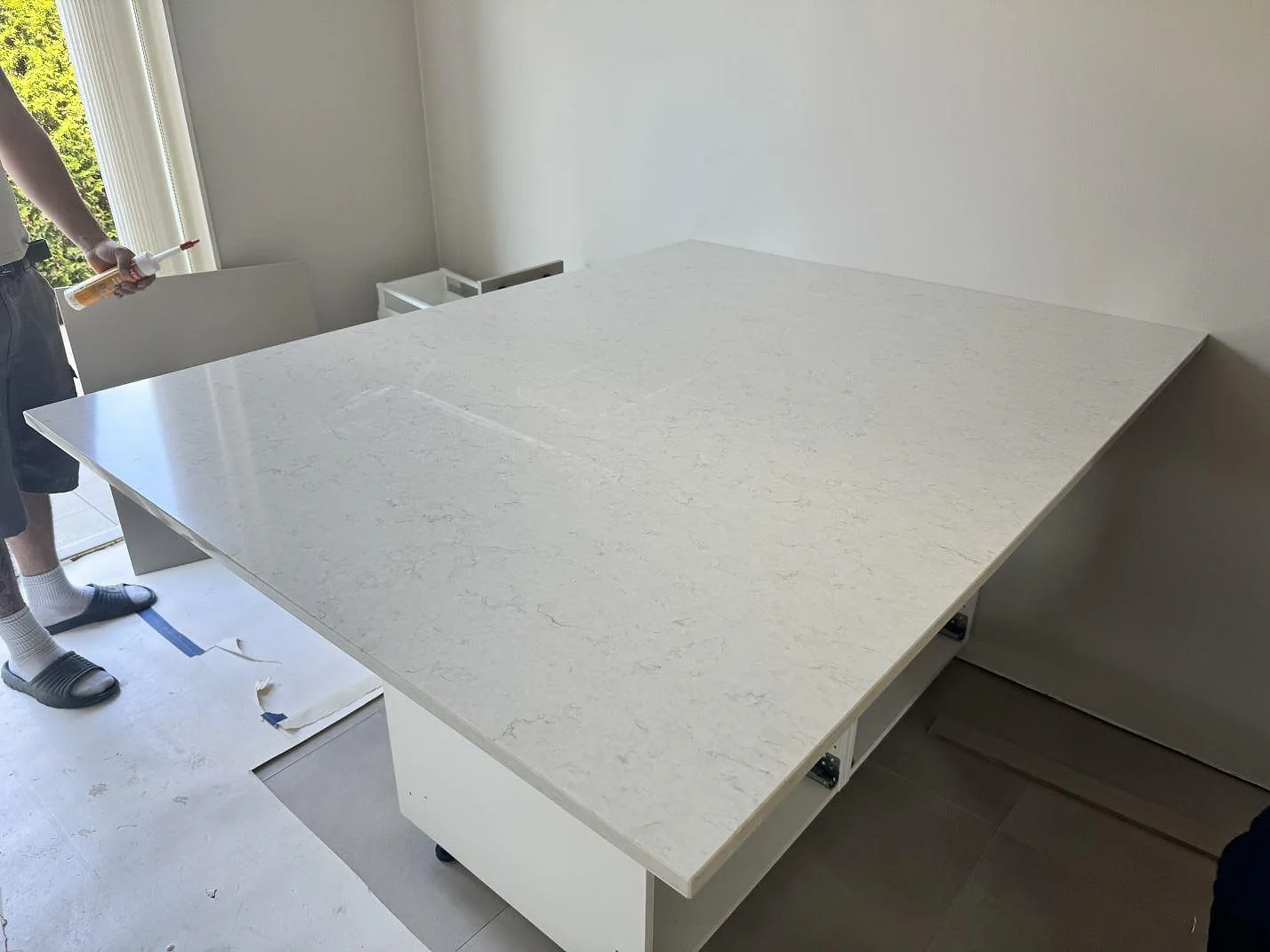 Fristående bänkyta i polerad Silestone Snowy Ibiza komposit på vita köksstommar under montering i Ojersjo.