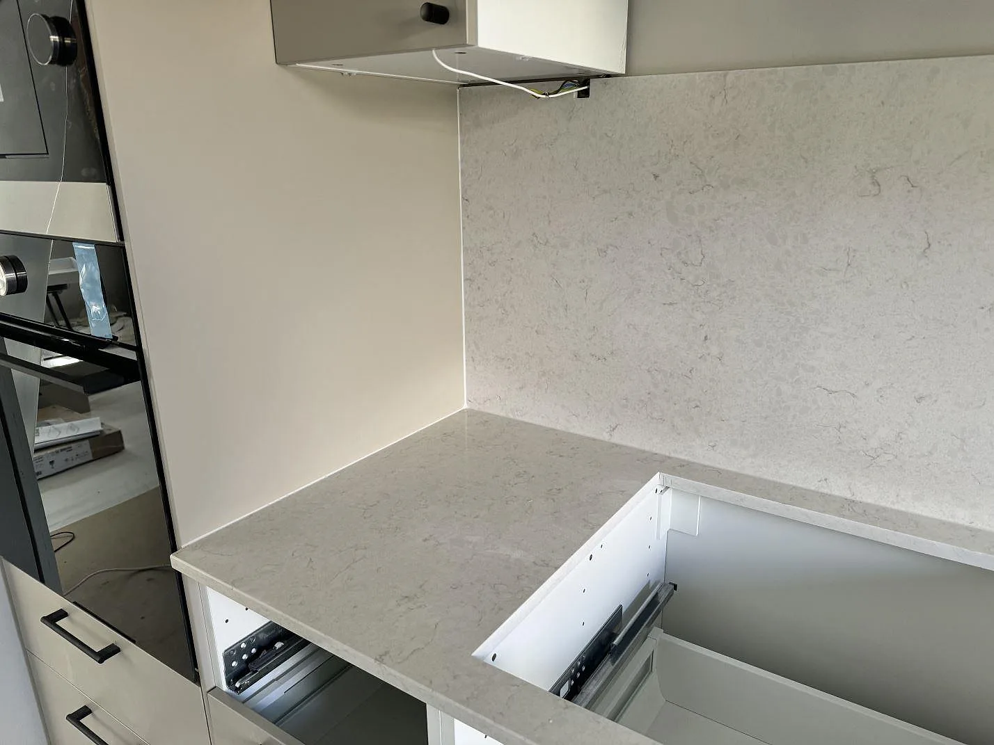 Köksbänkskiva i polerad Silestone Snowy Ibiza med hälluttag, väggbeklädnad och vita stommar i Ojersjo.