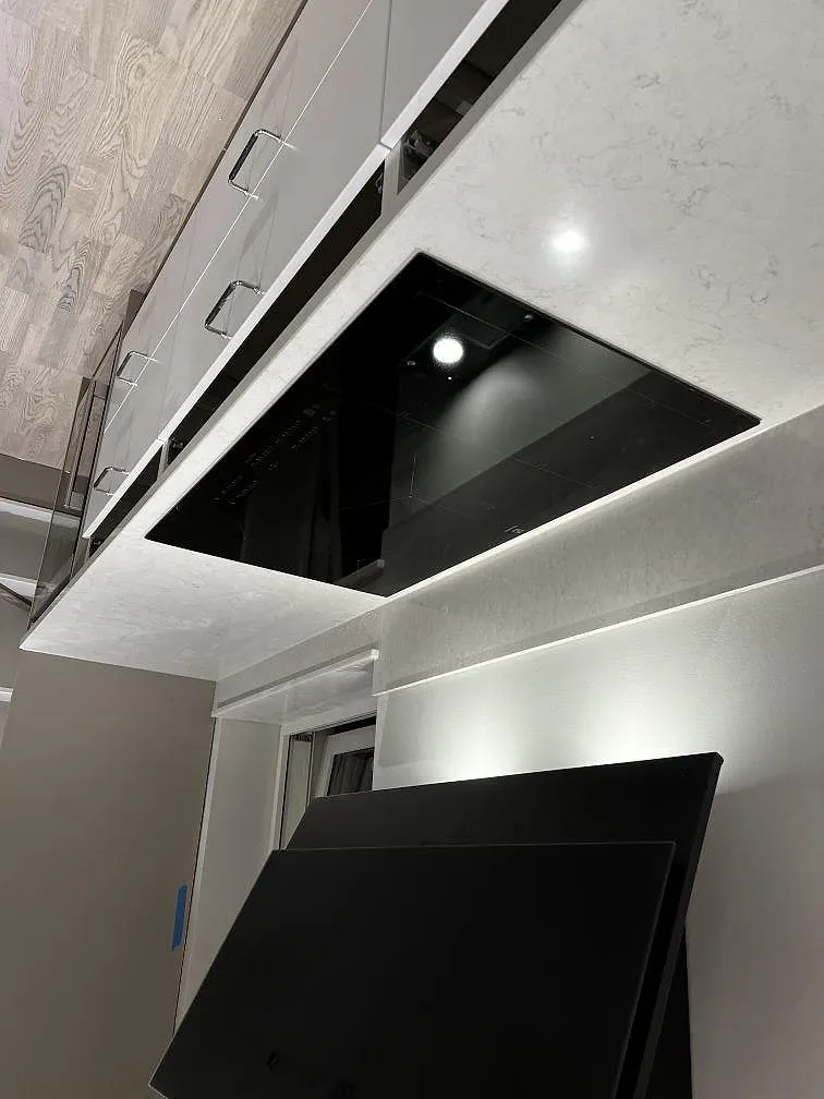 Vit Silestone Snowy Ibiza köksbänkskiva med polerad yta och induktionshäll bredvid ett svart högskåp i ett kök i Olofstorp.