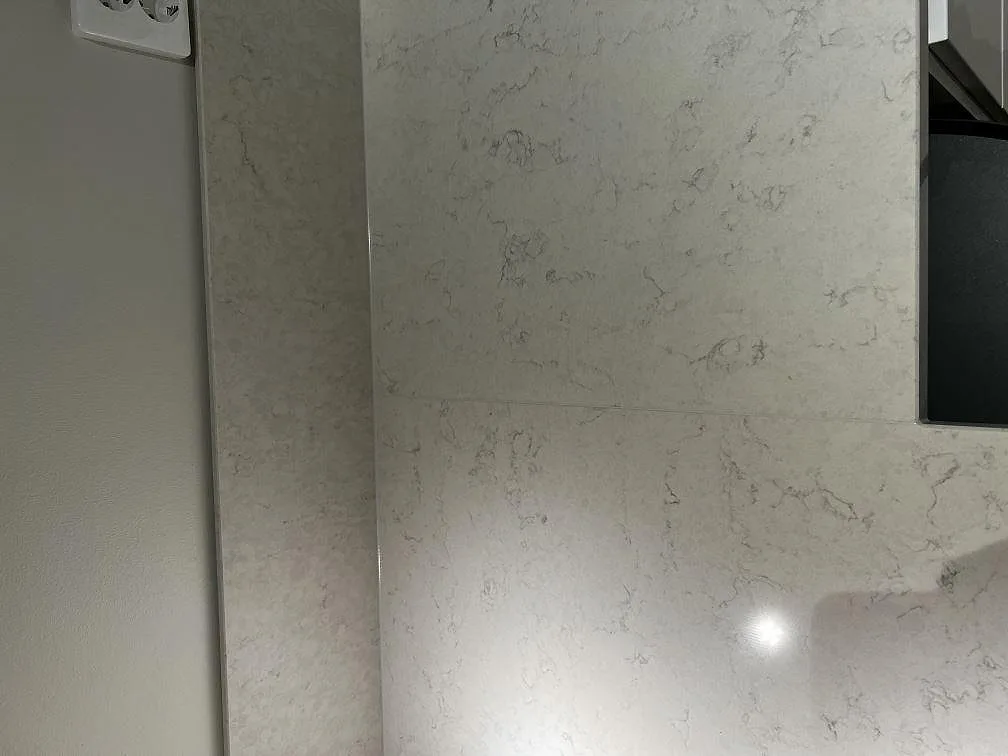 Detalj av den mjukt ådrade vita Silestone Snowy Ibiza-bänkskivan i polerad kvartskomposit i Olofstorp.