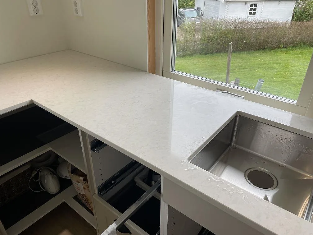 Köksbänkskiva i polerad Silestone Snowy Ibiza med underlimmad rostfri diskho och trädgårdsfönster i Olofstorp.