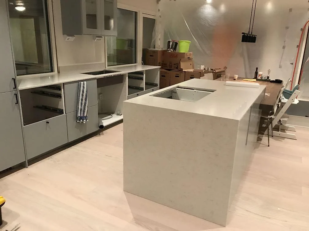Köksbänkskiva och köksö i vit Silestone Snowy Ibiza, polerad, under montering i ett kök i Onsala.