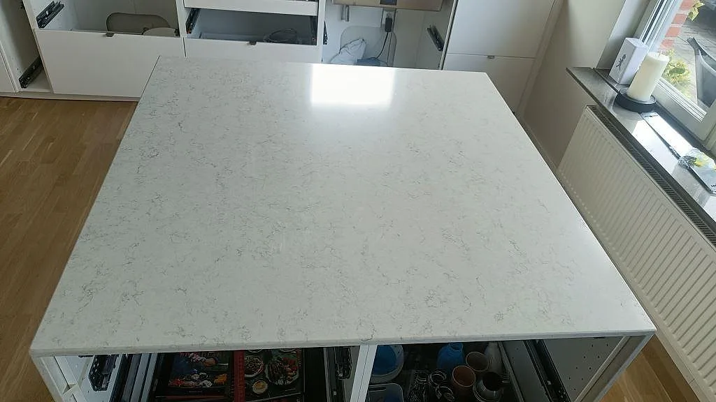 Köksö i Silestone Snowy Ibiza, polerad vit kvartskomposit med diskret grå ådring, sett ovanifrån i Oxie.