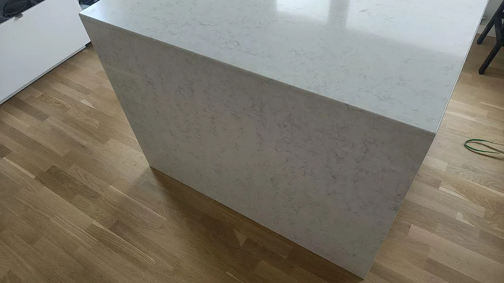 Köksö i Silestone Snowy Ibiza med nedfälld sida i polerad vit kvartskomposit i ett kök i Oxie.