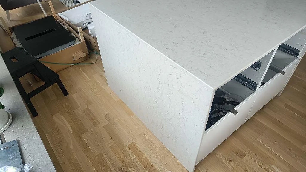 Köksö med vattenfallskant i Silestone Snowy Ibiza, polerad vit sten, i ett kök i Oxie.
