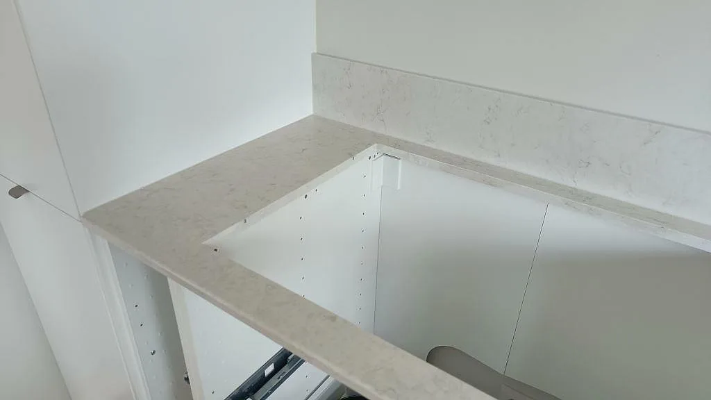 Bänkskiva i Silestone Snowy Ibiza med uppvikt stänkkant i samma sten i ett kök i Oxie.