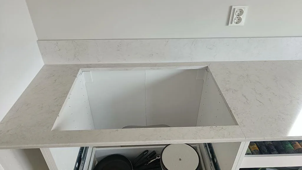 Bänkskiva i vit Silestone Snowy Ibiza med urtag för häll och uppvikt stänkkant i ett kök i Oxie.