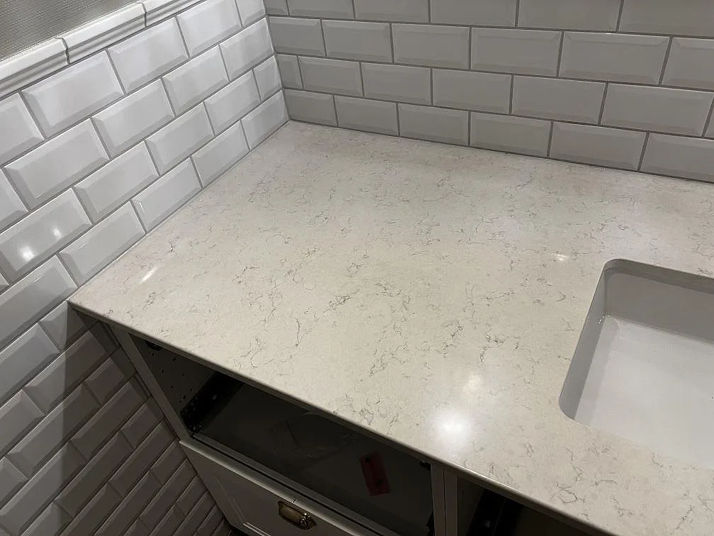 Detalj av polerad Silestone Snowy Ibiza som badrumsbänkskiva med grå ådring och handfatsöppning i Röke.
