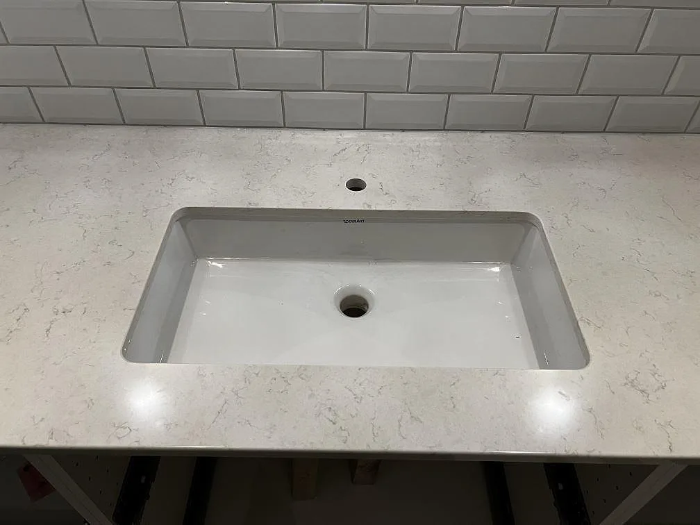 Närbild på underlimmat vitt handfat i 20 mm polerad Silestone Snowy Ibiza i ett badrum i Röke.