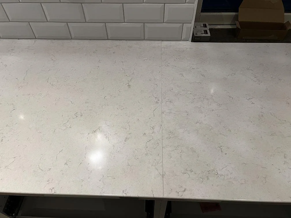 Detalj av skarv i polerad Silestone Snowy Ibiza på en lång badrumsbänkskiva med vitt kakel i Röke.