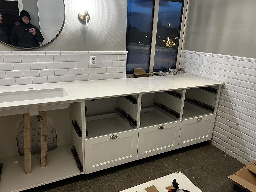 Lång bänkskiva i polerad Silestone Snowy Ibiza över vit dubbelkommod i ett badrum under montering i Röke.