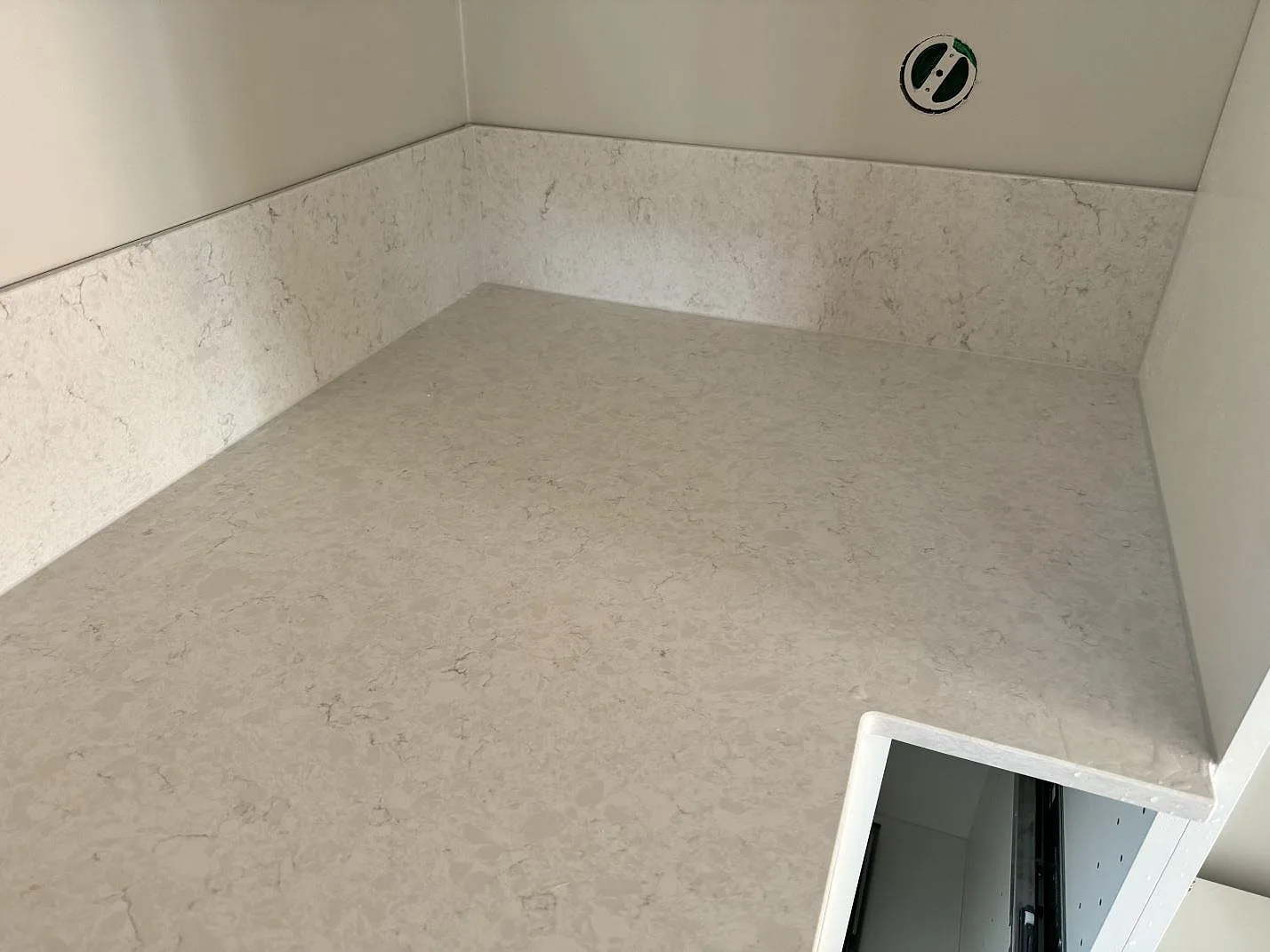 Hörn av köksbänkskiva i polerad Silestone Snowy Ibiza med matchande låg stänkkant och ljus grå ådring i Rydebäck.