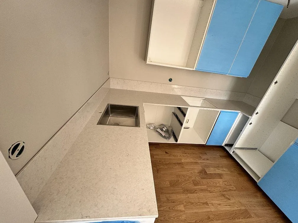 Köksbänkskiva i polerad Silestone Snowy Ibiza med synlig diskho, låg stänkkant och öppna köksstommar i Rydebäck.