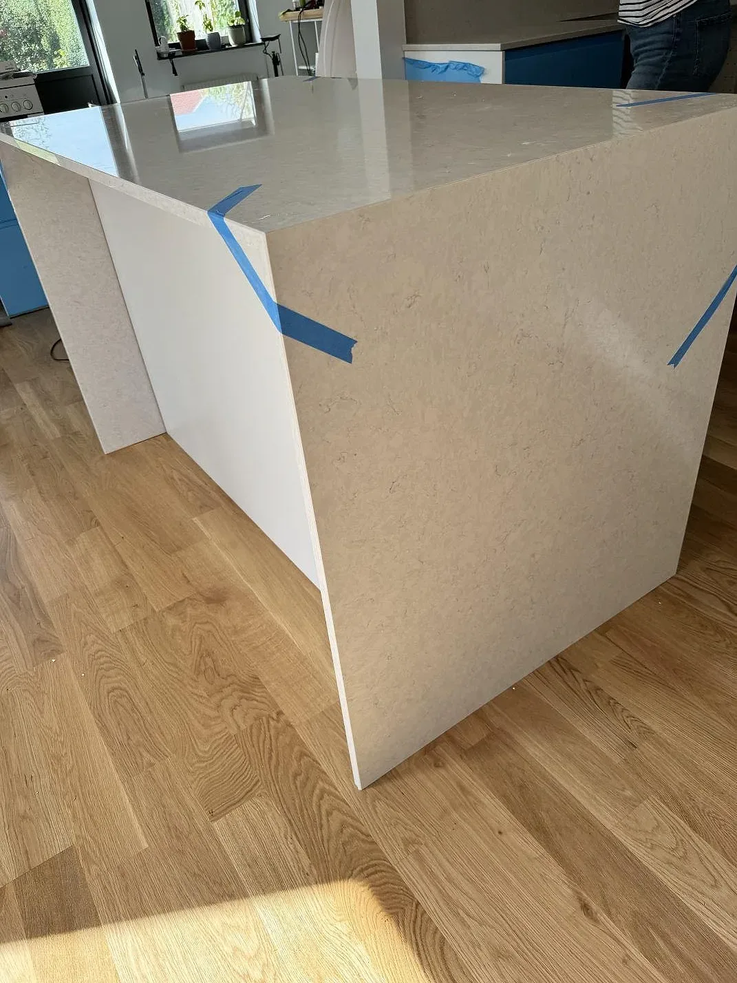 Polerad Silestone Snowy Ibiza på separat arbetsyta med ljus ådring, blå skyddstejp och stenklädd gavel i Rydebäck.